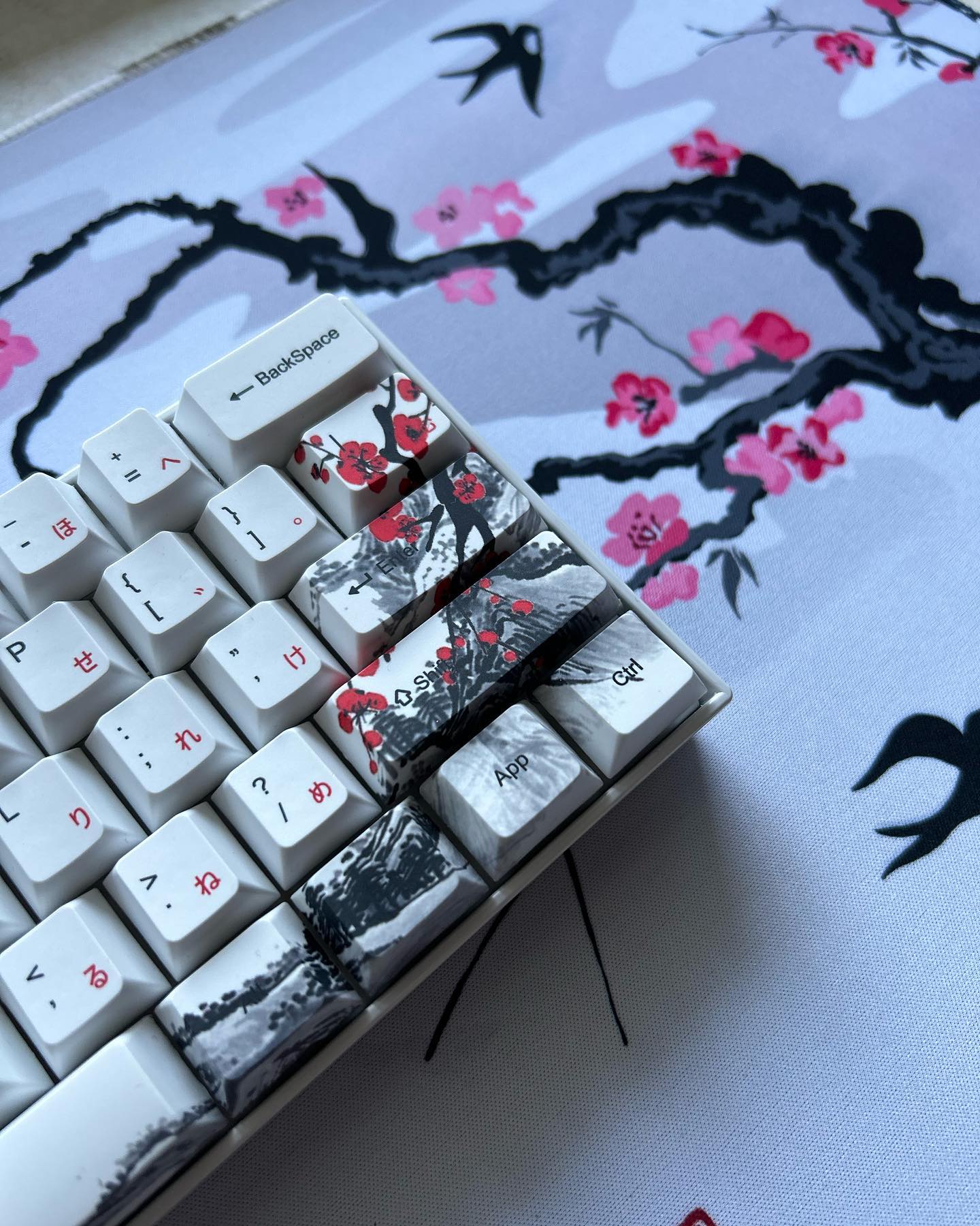 Close-up of custom keycaps with a cherry blossom desk mat